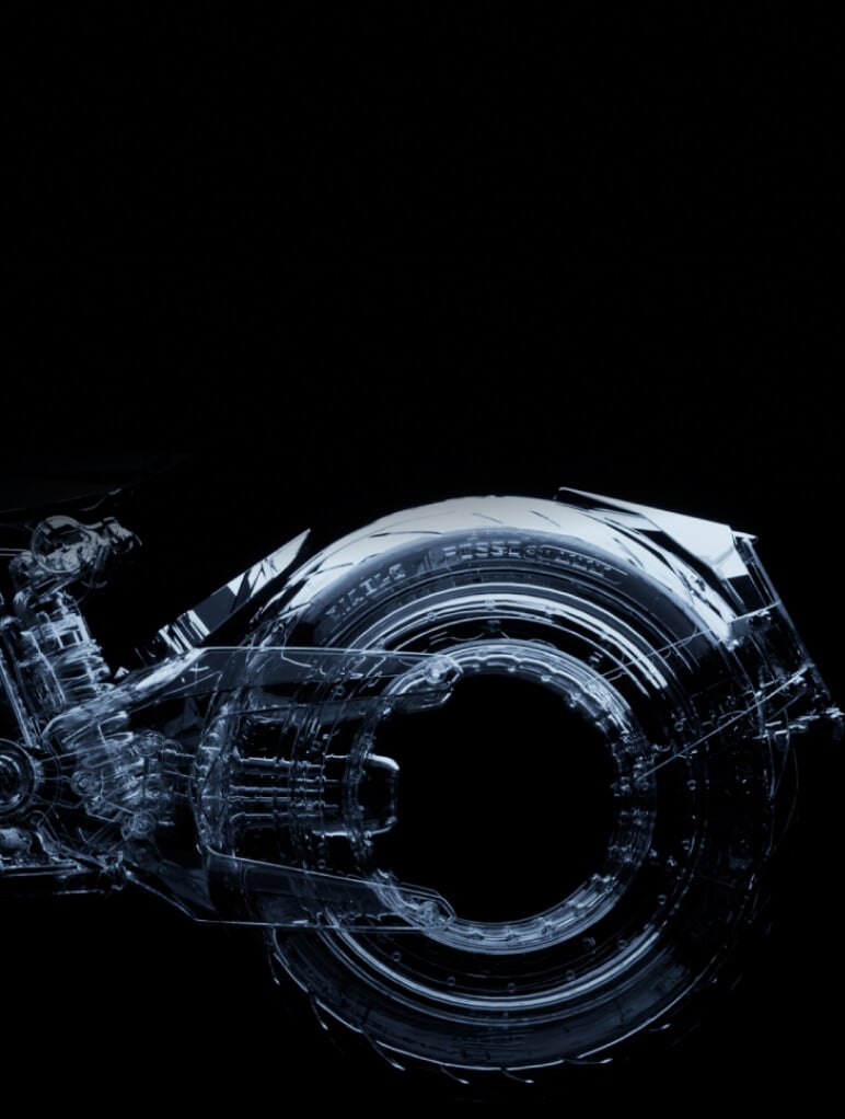 A transparent, futuristic motorcycle wheel and partial frame, illuminated against a dark background. The intricate details of the wheel's design are highlighted, showcasing an innovative and sleek structure.