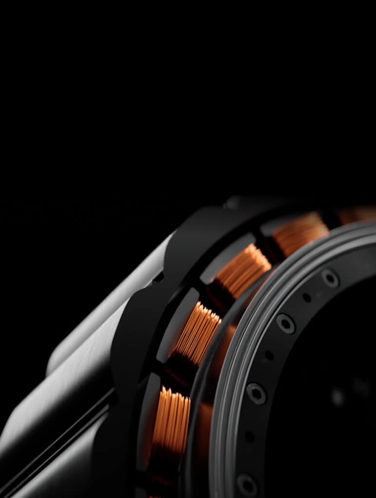 Close-up of a sleek metallic object with copper coils, possibly a motor or mechanical component, against a black background. The image highlights the texture and intricate details of the coils and housing.