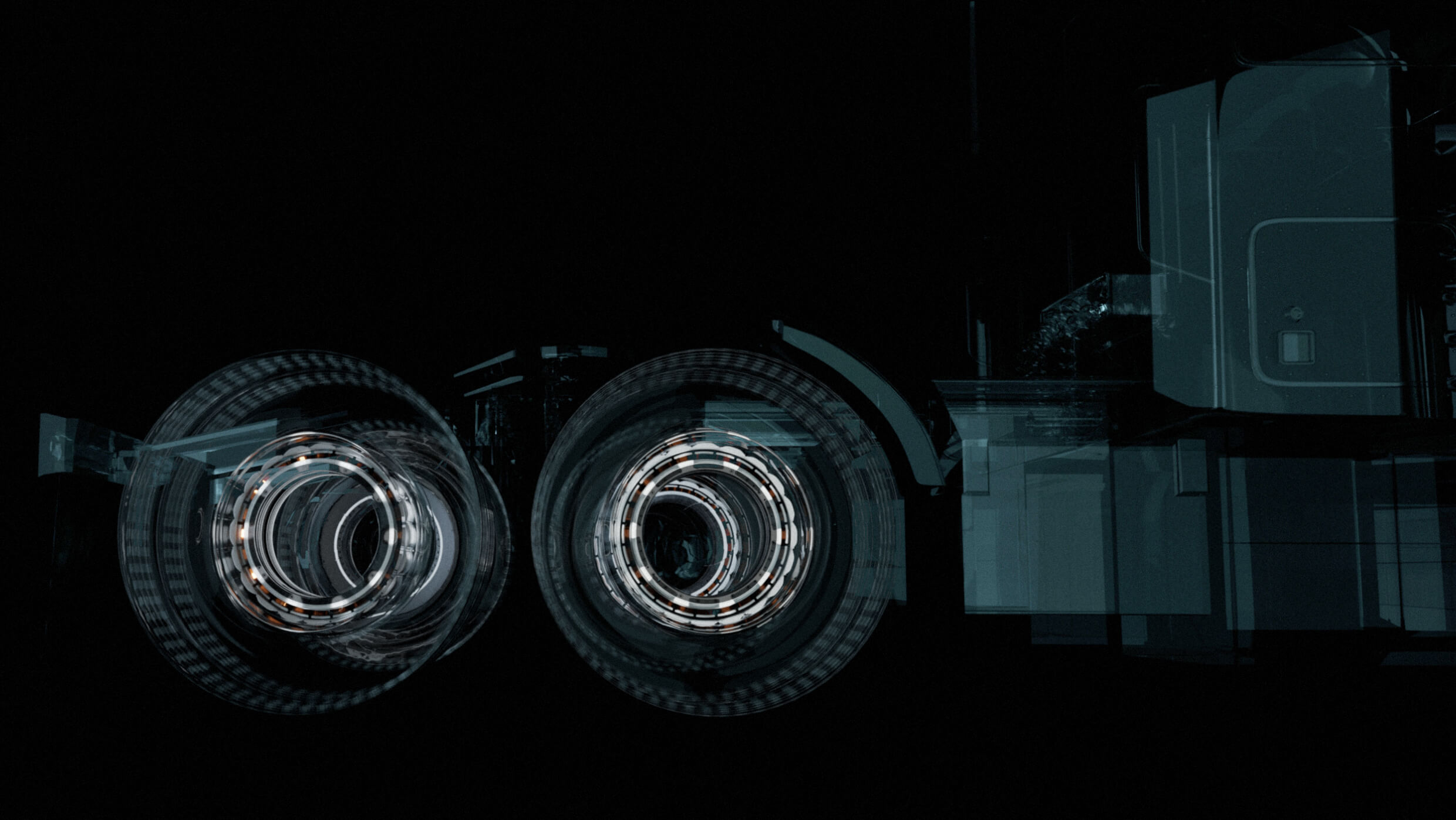 Abstract image featuring two circular light patterns resembling wheels, set against a dark background with faint geometric shapes, suggesting a futuristic vehicle design. The composition has a layered, translucent quality.